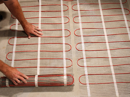 A ComfortTile floor heating mat being installed for a heated basement floor. ComfortTile floor heating mat being installed.